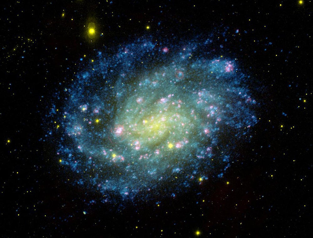 photo of a spiral galaxy that depicts the colors of Brazil – green, yellow and blue